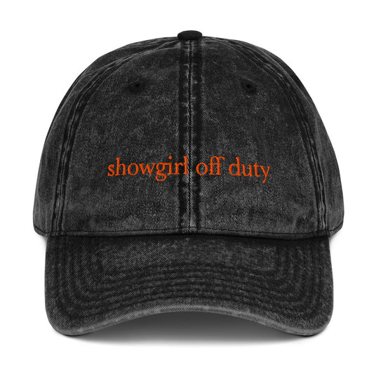 Black denim cap with 'showgirl off duty' text in orange on a white background