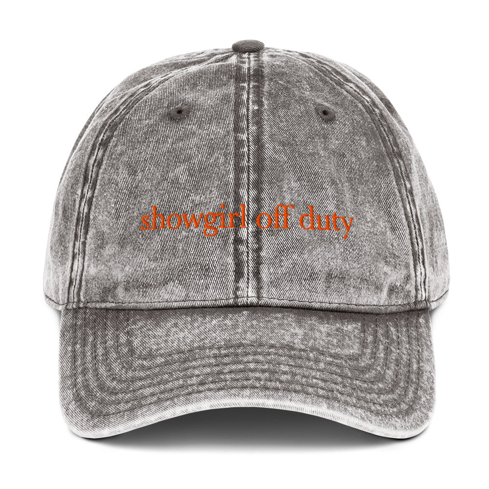 Gray denim cap with 'showgirl off duty' text on a white background