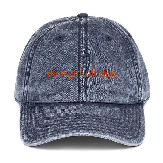 Blue denim cap with 'showgirl off duty' text on a white background