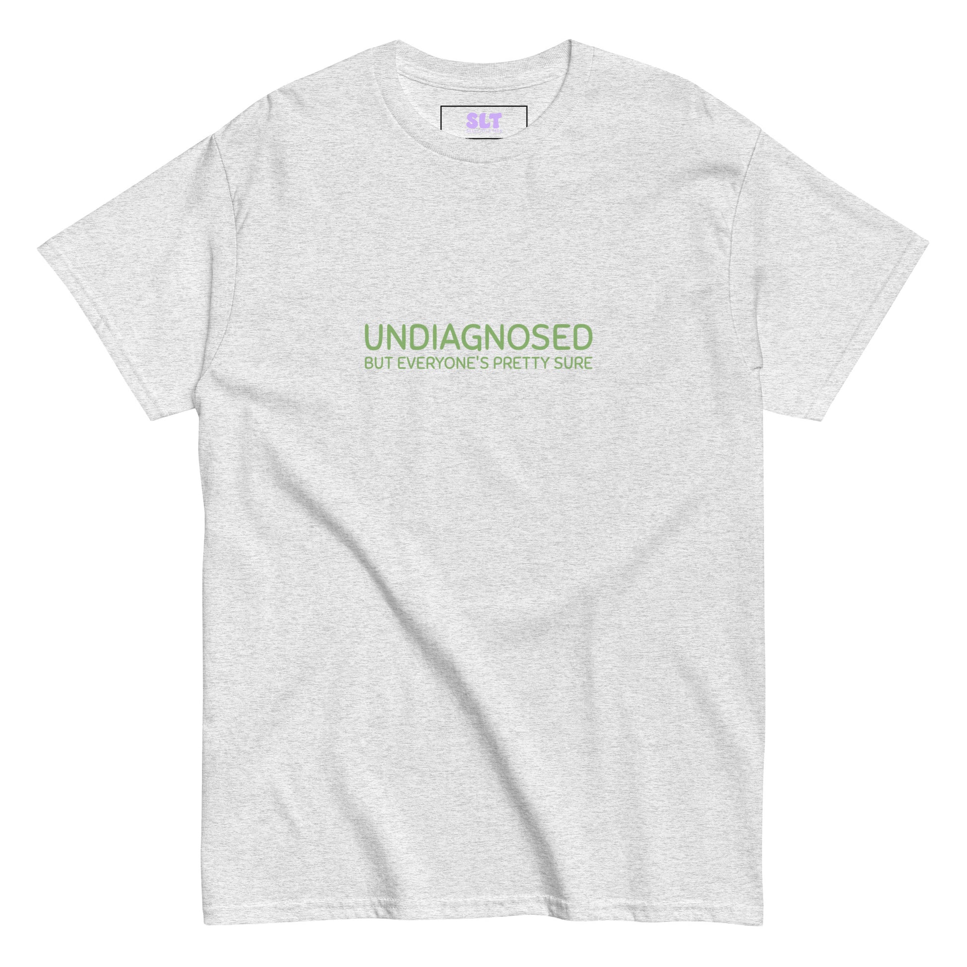 White t-shirt with “Undiagnosed But Everyone’s Pretty Sure” slogan, folded neatly on a lilac backdrop.